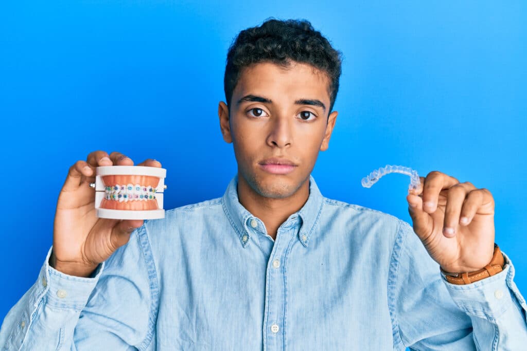 Atención De Emergencias De Ortodoncia En Las Vegas 3 Sad Teenager Holding A Model Of Teeth With Braces And A Retainer 1024X683 1
