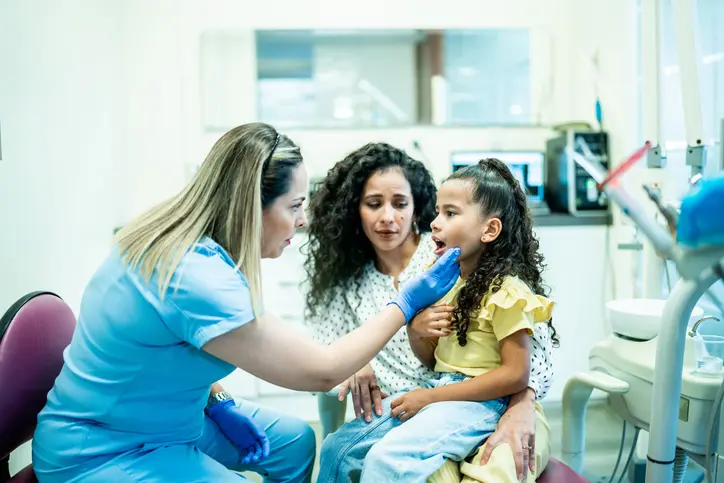 Qué Hacer Cuando Su Hijo Tiene Mesiodens 1 Odontopediatra Revisando Los Dientes De Una Niña En El Consultorio Dental Con Su Madre Presente